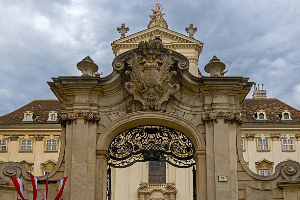 Vienna, Austria - August, 01, 2025: Ornate baroque-style entrance gate featuring an imperial double-headed eagle crest, leading to a historic palace in Vienna, Austria.