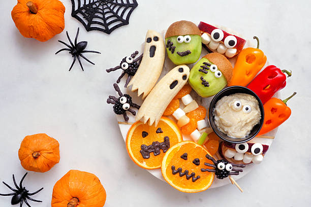 istock Healthy Halloween fruit and vegetable platter. Overhead view table scene over a dark stone background. 2231683682
