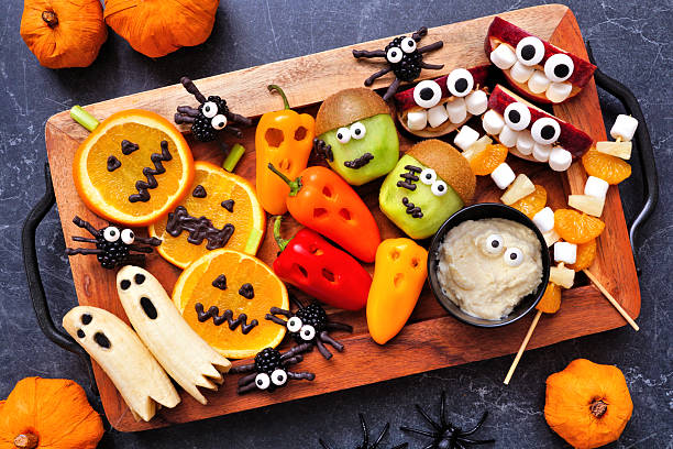 istock Healthy Halloween fruit and vegetable platter. Above view table scene over a dark stone background. 2231683684