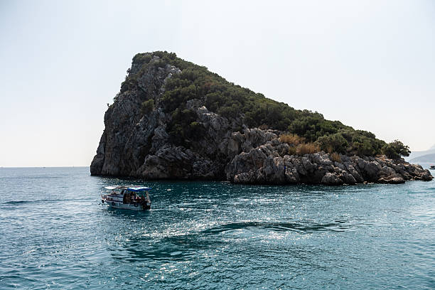 Antalya, Turkey - October 7, 2023. Wide angle shot of the rocky coast of the mediterranian, with a little yacht in front of the rock.
