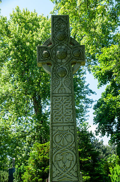 istock Ancient Stone Cross with Celtic Patterns in a Lush Green Forest 2231696060
