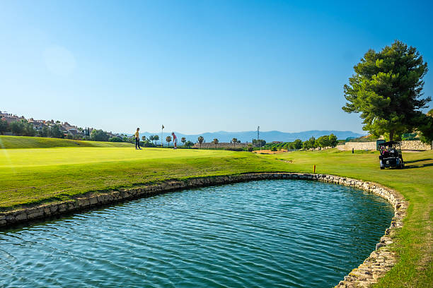 istock Golfers playing on a sunny green with water hazard 2231696412