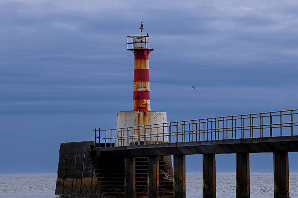 istock Weathered Red and White Lighthouse by the Pier 2231700369