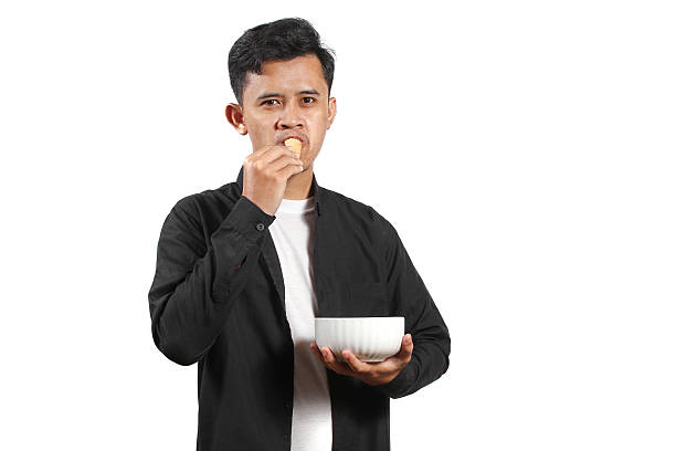 istock Asian man carrying a bowl eating crackers isolated on white background 2231705472
