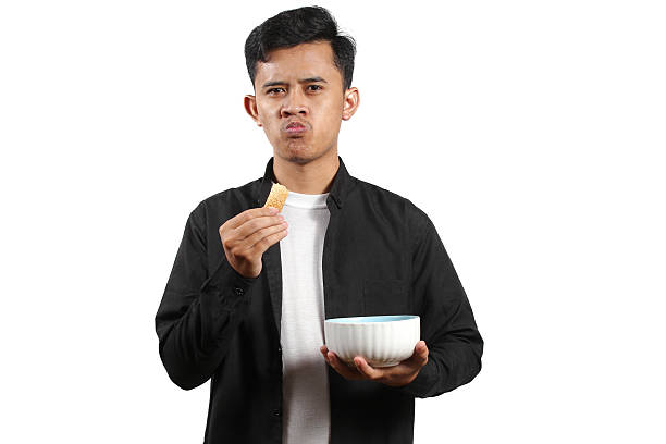 Asian man carrying a bowl eating crackers isolated on white background