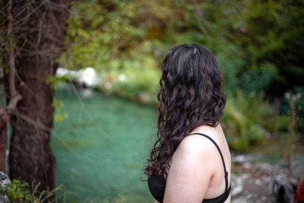 Solo female adventurer beside natural spring in green jungle — eco travel, untouched nature, remote paradise, exploration journey