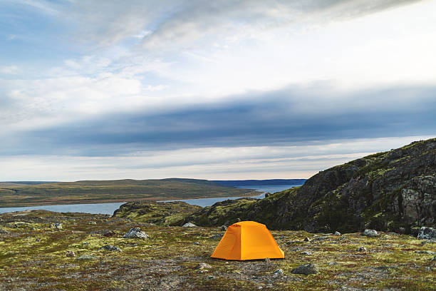 Tent near mountain lake at camping in twilight