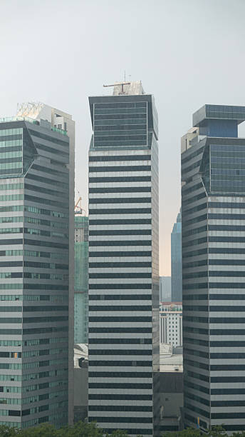 istock Urban skyline study: Petronas-like tower reflected in glass, striped office blocks, and sleek modern high-rises rising under overcast skies in a bustling city 2231722715