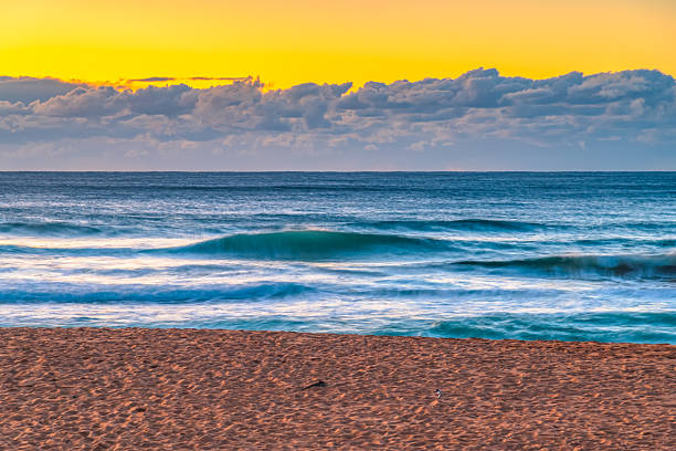 Sunrise seascape with low cloud bank and waves at Bilgola Beach on the Northern Beaches of Sydney, NSW, Australia.