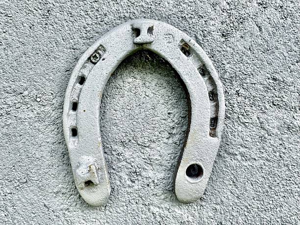 Old metal horseshoe hanging on concrete wall as symbol of good luck