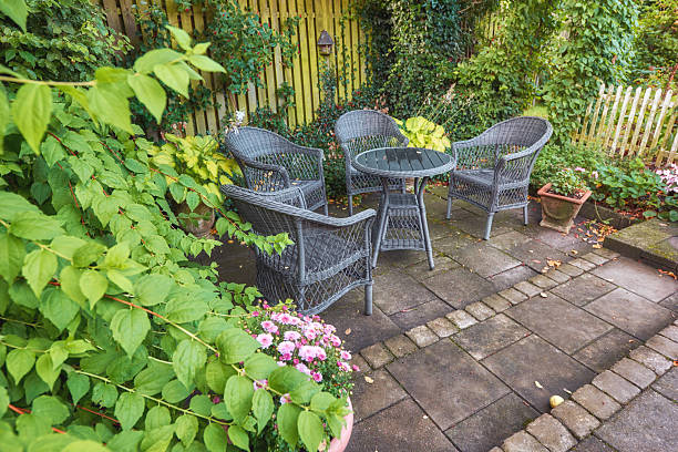 istock Charming Garden Setting with Wicker Chairs Surrounded by Lush Greenery and Flowers 2231731379