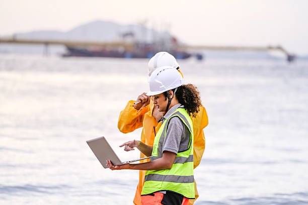 istock Two field scientists in PPE gear analyzing seawater samples using test tubes and a laptop. Environmental monitoring and pollution control on the coastline are depicted. 2231734123