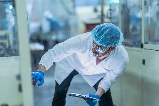 istock A food processing supervisor wearing protective gear and holding a clipboard, inspecting operations between machinery in a factory, emphasizing hygiene, safety, and quality control in production 2231736920