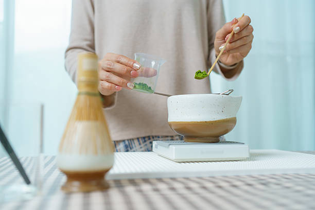 istock Asian woman preparing traditional Japanese matcha tea at home using bamboo tools, sifting matcha powder with care and precision. 2231737853
