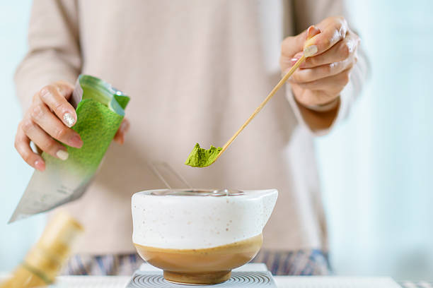 istock Asian woman preparing traditional Japanese matcha tea at home using bamboo tools, sifting matcha powder with care and precision. 2231737880