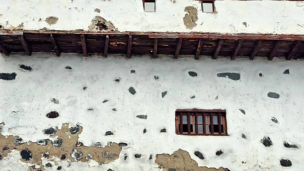 A captivating historic, weathered wall adorned with a charming window and rich rustic texture