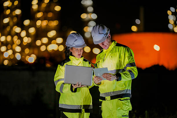 istock Two diverse engineers coordinate operations on a night shift. The man uses a radio while the woman explains data from a digital tablet, a concept for industrial communication. 2231743912