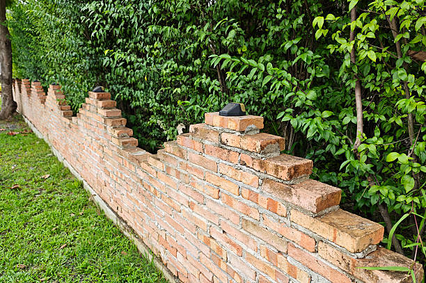 The brick wall, fence barrier is designed with a hole on top of wall in Asian style with garden grass field in the foreground