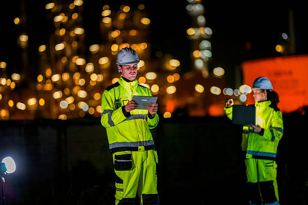 istock Two diverse engineers coordinate operations on a night shift. The man uses a radio while the woman explains data from a digital tablet, a concept for industrial communication. 2231744951