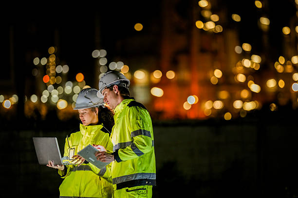 istock Two diverse engineers coordinate operations on a night shift. The man uses a radio while the woman explains data from a digital tablet, a concept for industrial communication. 2231744988