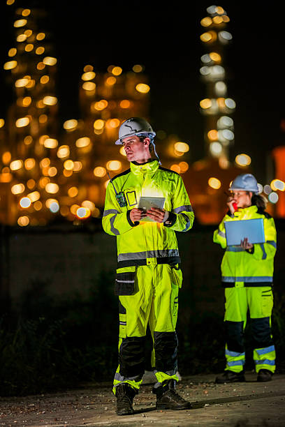 istock Two diverse engineers coordinate operations on a night shift. The man uses a radio while the woman explains data from a digital tablet, a concept for industrial communication. 2231745166