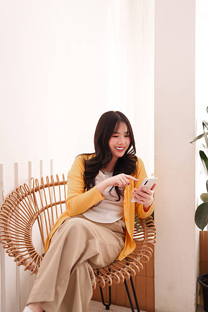 istock Young Asian woman smiles using smartphone modern cafe cheerful relaxed mobile communication social media browsing online freelance work lifestyle 2231749846