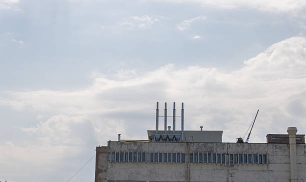 istock Industrial rooftop with chimneys and ventilation pipes against cloudy sky 2231751774