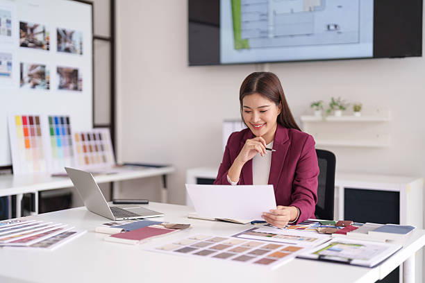istock Asian Woman Architect Professional Reviewing House Design Plans Material Samples Bright Modern Office Creating Home Concepts 2231757629