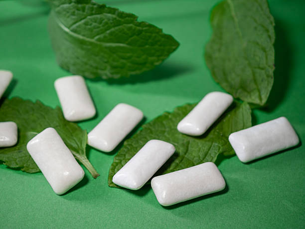 istock Mint chewing gum, white dragees lying on spearmint leaves 2231767827