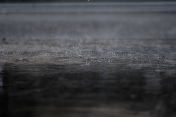 raining on the concrete walk way full with rain droplets splash ring bounce off the surface of water with reflected of white cloudy sky
