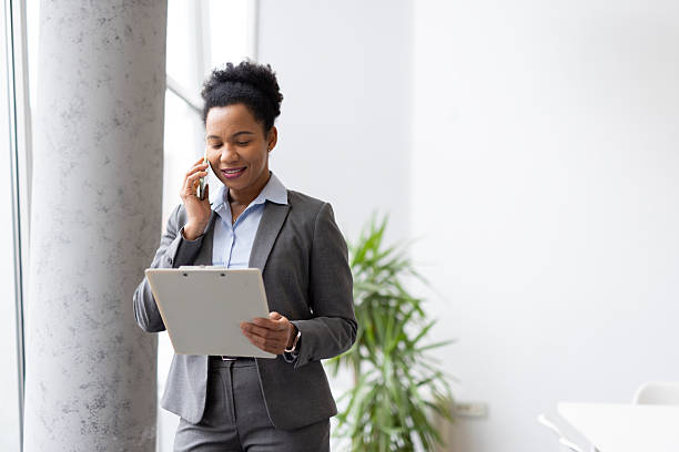 istock Professional woman multitasking, handling phone call while examining paperwork near sunlit office windows 2231772228