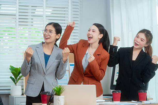 istock Three Asian women in formal suits collaborate at a desk, discussing documents in a modern office. teamwork, strategy planning, creative problem-solving in professional business environment. 2231774027