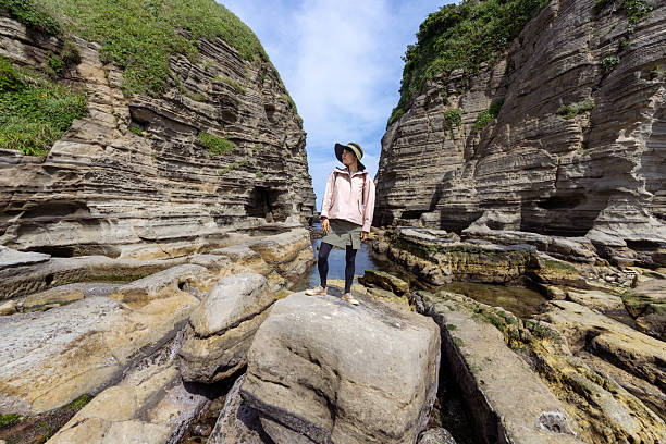 Female tourist standing on rock by Pacific Ocean