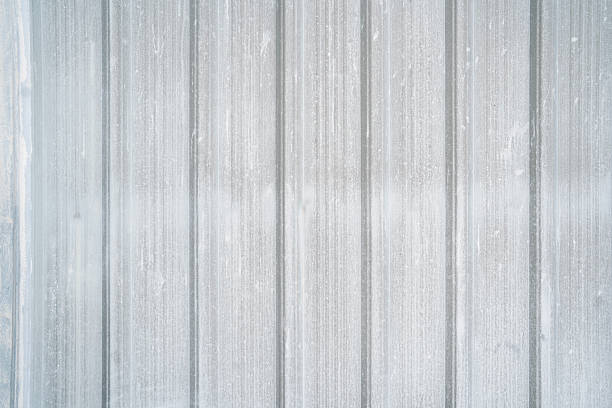Close-up of a silver painted metal door featuring vertical line texture. Industrial style surface background for architecture, construction, and design themes.