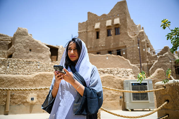 istock Young woman in a blue headscarf using her mobile phone while standing outside heritage buildings in Riyadh 2231784226