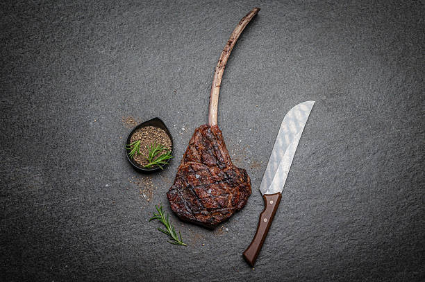 istock Grilled Tomahawk Steak on Slate Surface with Knife and Rosemary Garnish 2231785435