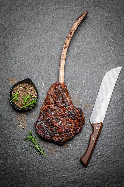 istock Perfectly Grilled Tomahawk Steak with Herbs and Knife on Stone Surface 2231785452