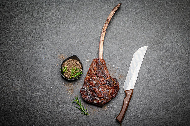 istock Grilled Tomahawk Steak with Knife and Seasonings on a Dark Surface 2231785469
