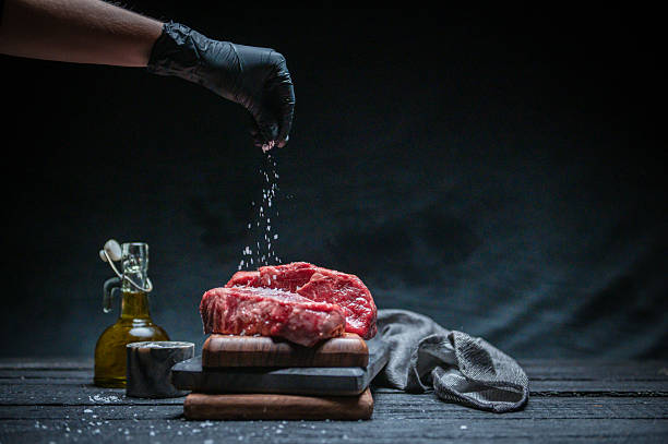 Chef Preparing Fresh Steak With Salt and Olive Oil in a Dark Setting