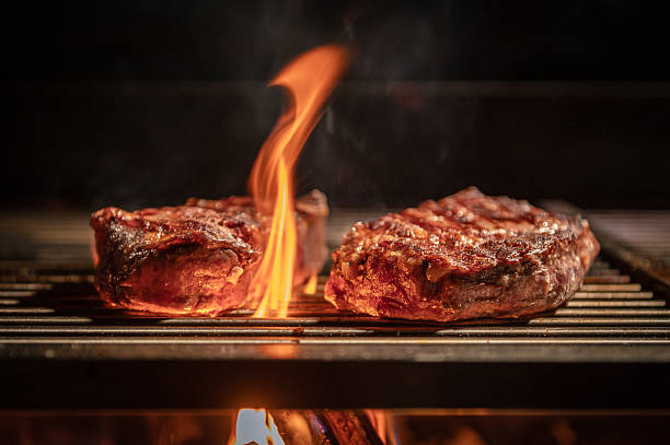 Grilled Steaks on Fire Flame with Delicious Sizzling on Barbecue Grill