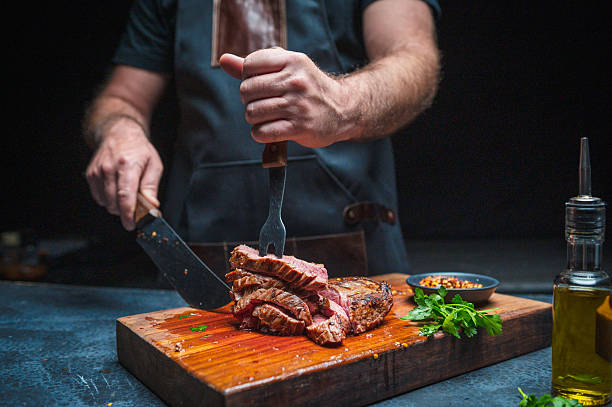 istock Chef Preparing Juicy Steak on Wooden Board with Fresh Ingredients 2231785921