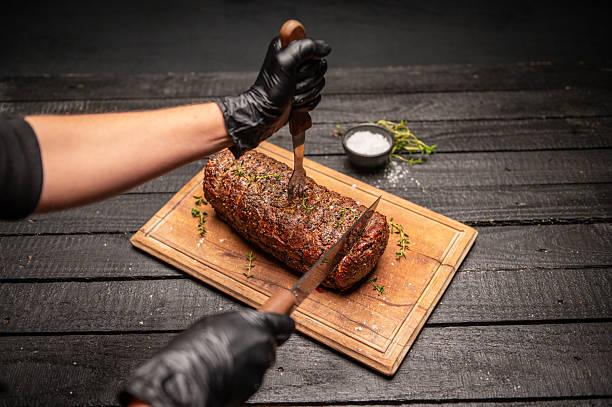 Chef Slicing a Perfectly Cooked Beef Roast on a Rustic Cutting Board