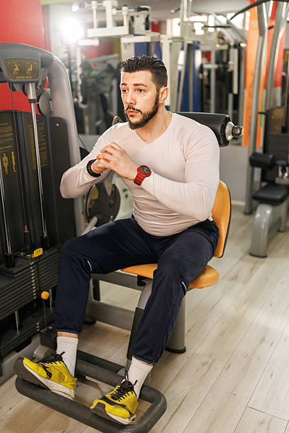 istock Muscular young man exercising on machine in the gym 2231789418