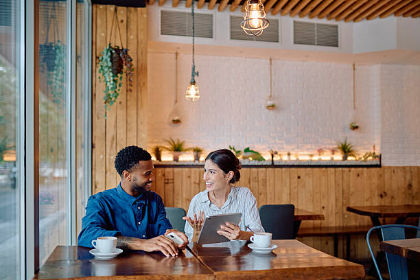 istock Business partners having a meeting at a cafe, discussing a project on a digital tablet 2231789937
