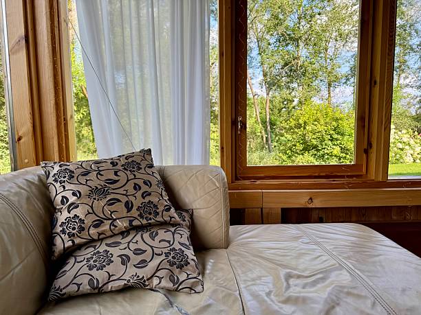 istock Cozy sofa with pillows by sunny wooden window 2231791119