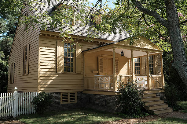 Williamsburg, Virginia: USA  August 23, 2025:  In the city of Colonial Williamsburg sits a home from the 1700's on a shaded piece of land.  The house is painted in a beautiful yellow color.
