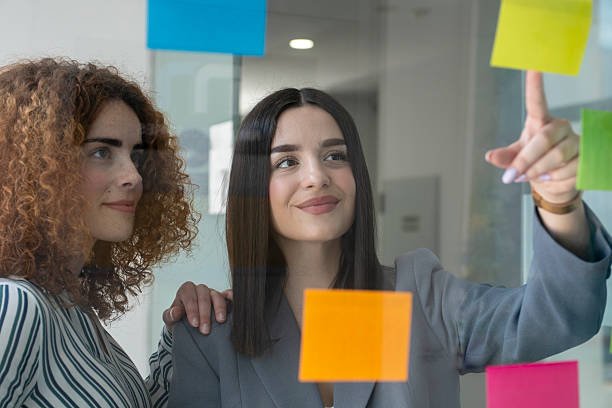 istock Businesswomen planning strategy using sticky notes on glass wall in office 2231796851