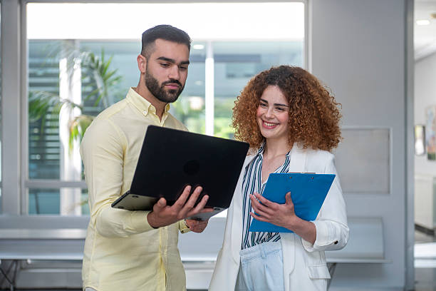 istock Business colleagues collaborating on project using laptop and clipboard in office 2231797138