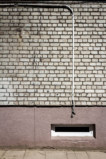 istock White brick wall with some cables and basement window 2231800898