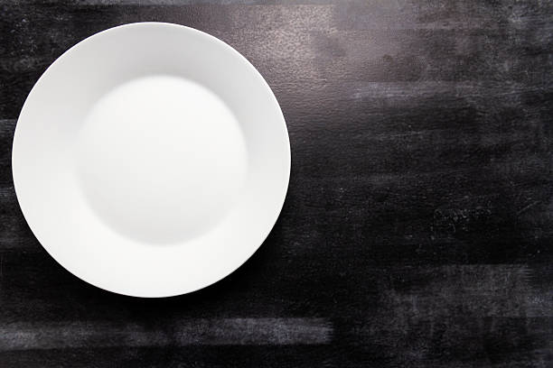 istock Big white plate on black chalkboard background 2231801140